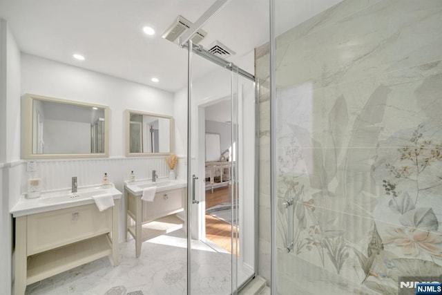 bathroom featuring a shower stall, two vanities, marble finish floor, and a sink