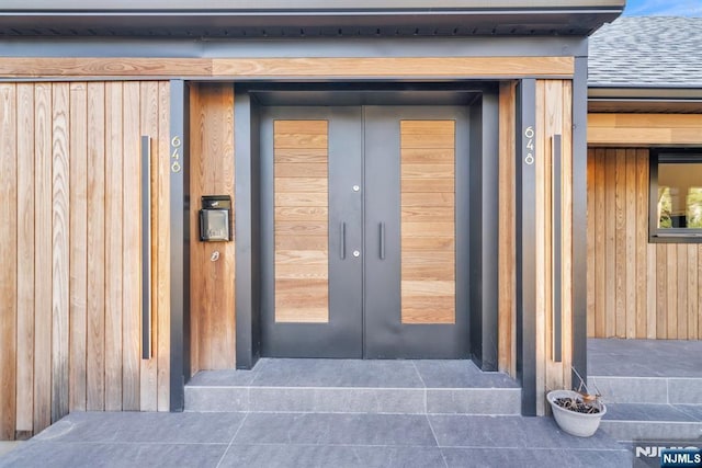 entrance to property featuring french doors and roof with shingles