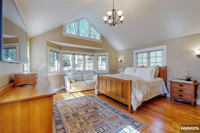 bedroom with light wood-style flooring, a notable chandelier, baseboards, and high vaulted ceiling