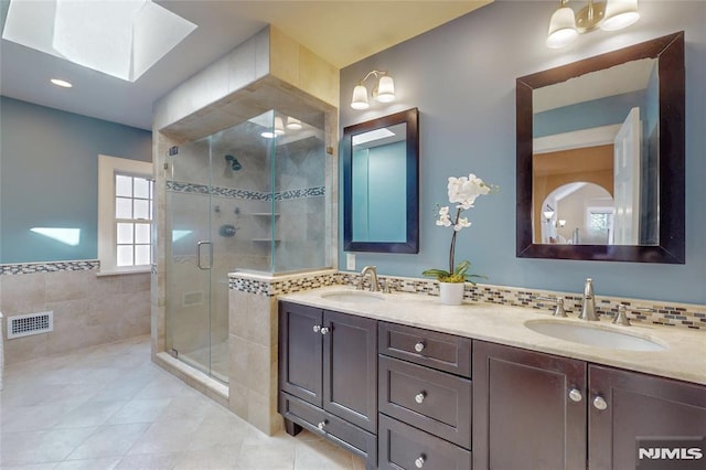 full bath with a sink, visible vents, a shower stall, and tile patterned flooring