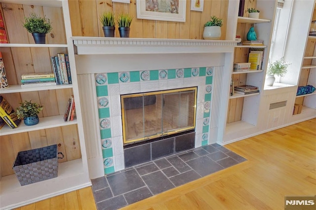 details featuring built in features, wood finished floors, and a tile fireplace