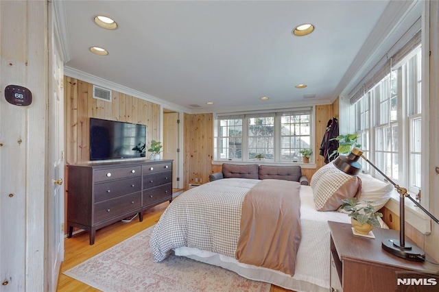 bedroom with wood finished floors, multiple windows, and ornamental molding