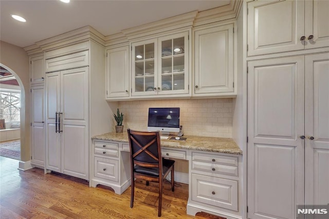 home office with recessed lighting, arched walkways, built in desk, and light wood finished floors