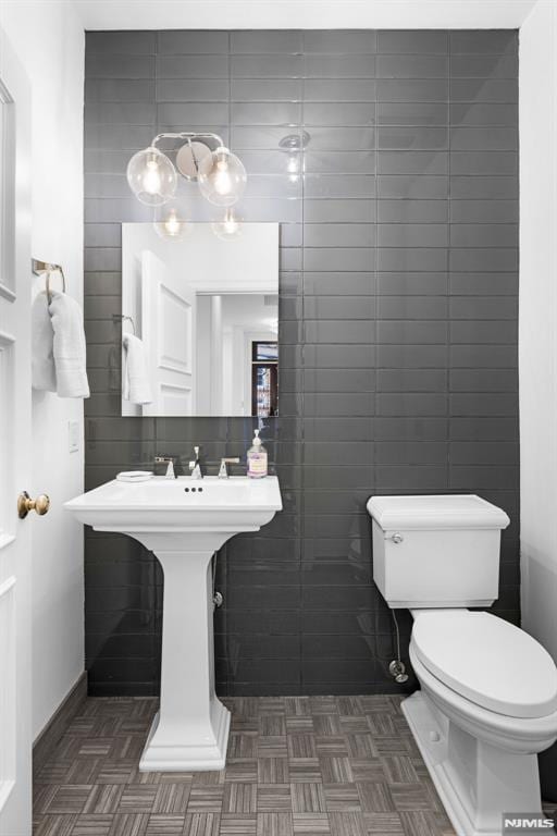 half bathroom with toilet and tile walls