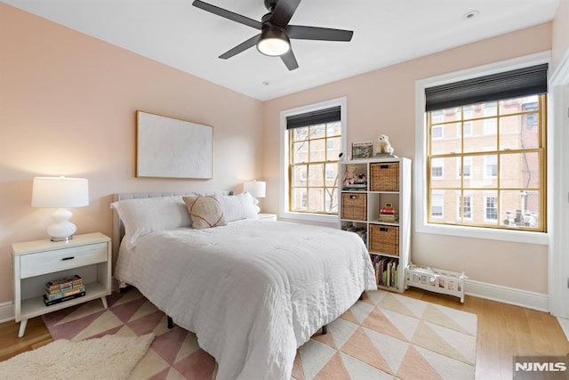 bedroom with light wood-type flooring, baseboards, and a ceiling fan