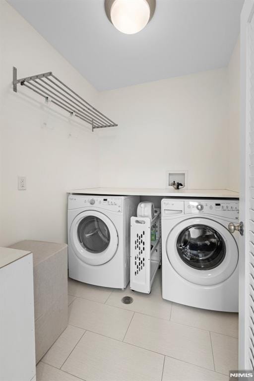 washroom featuring washer and clothes dryer, laundry area, and light tile patterned floors