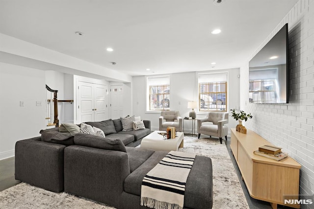 living room featuring recessed lighting, stairway, baseboards, and brick wall