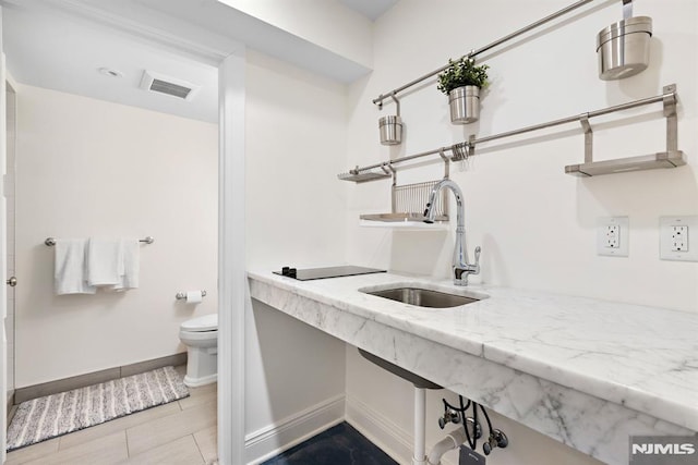 full bathroom with toilet, baseboards, visible vents, and a sink