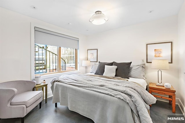 bedroom featuring finished concrete flooring and baseboards