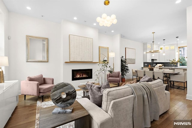 living room featuring a glass covered fireplace, recessed lighting, wood-type flooring, and a chandelier