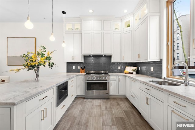 kitchen with a sink, high end stainless steel range oven, a peninsula, white cabinets, and black microwave