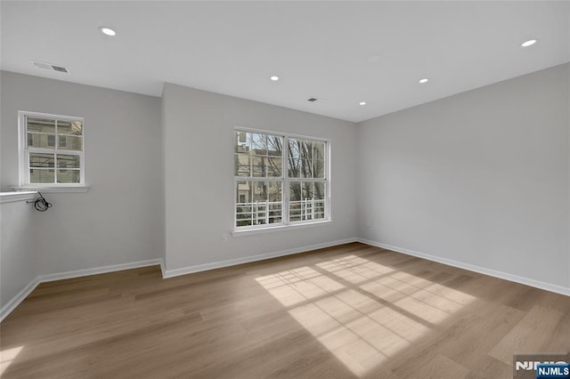 unfurnished room featuring recessed lighting, wood finished floors, visible vents, and baseboards