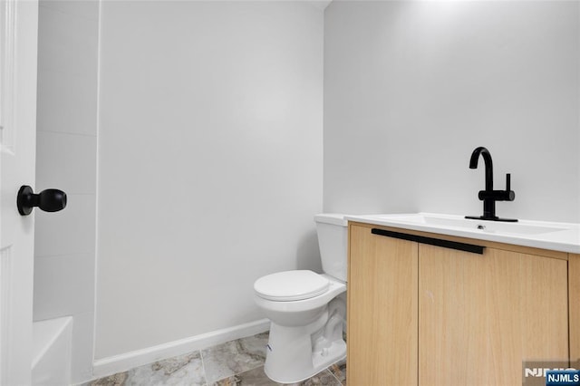 bathroom featuring vanity, toilet, baseboards, and a bathing tub