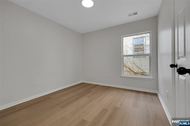 empty room featuring visible vents, baseboards, and light wood-style floors