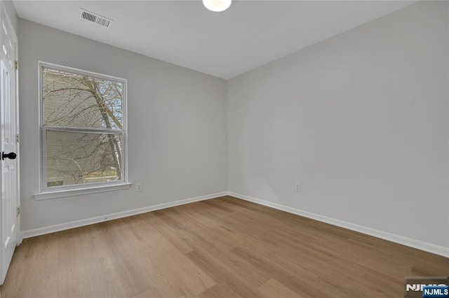 unfurnished room with wood finished floors, visible vents, and baseboards