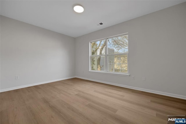 unfurnished room with visible vents, baseboards, and wood finished floors