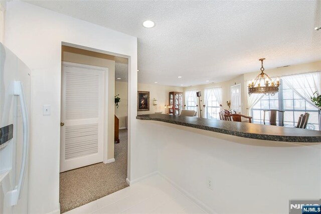 kitchen featuring dark countertops, pendant lighting, a textured ceiling, and white refrigerator with ice dispenser