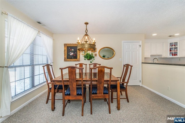 dining space featuring light carpet, visible vents, baseboards, and an inviting chandelier