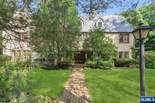 english style home with stucco siding and a front yard