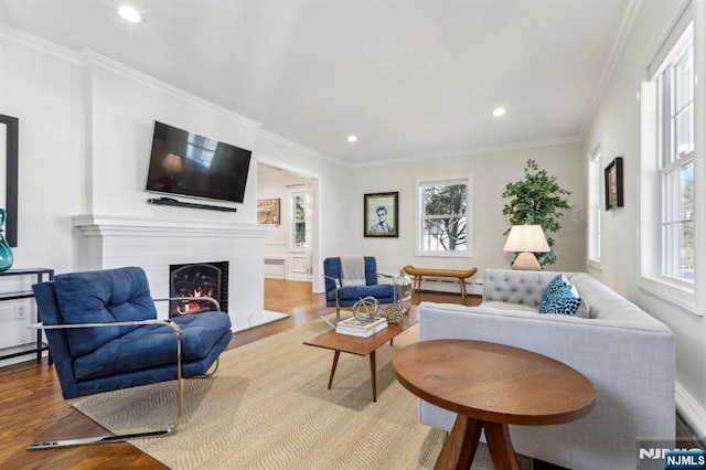 living area featuring a wealth of natural light, ornamental molding, and wood finished floors