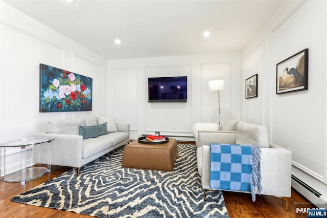 living area with a decorative wall, recessed lighting, wood finished floors, and baseboard heating