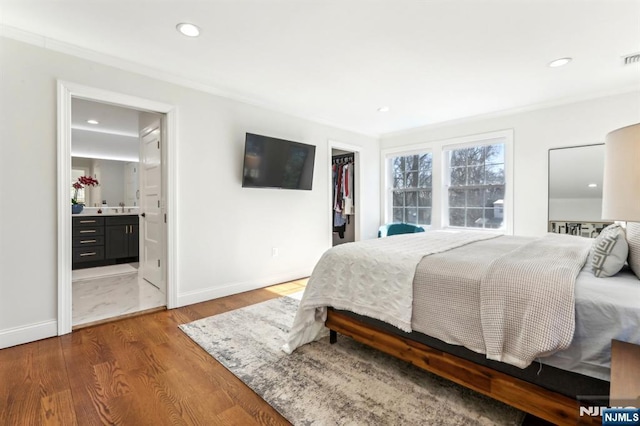 bedroom with recessed lighting, a walk in closet, baseboards, and wood finished floors