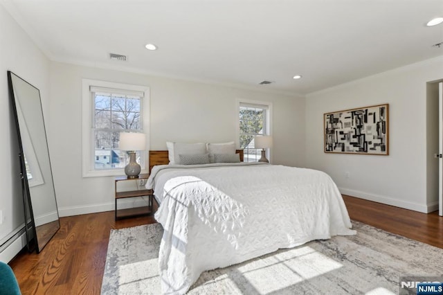 bedroom with baseboards, wood finished floors, visible vents, and a baseboard radiator