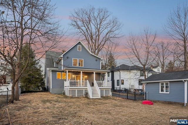 rear view of property with stairway, covered porch, a fenced backyard, a yard, and a ceiling fan