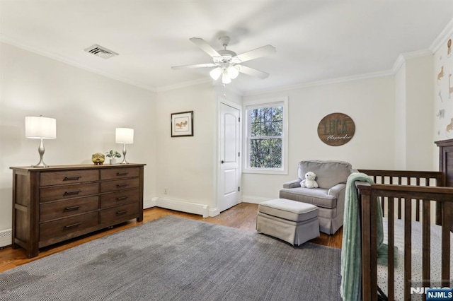 bedroom with visible vents, baseboards, wood finished floors, and ornamental molding