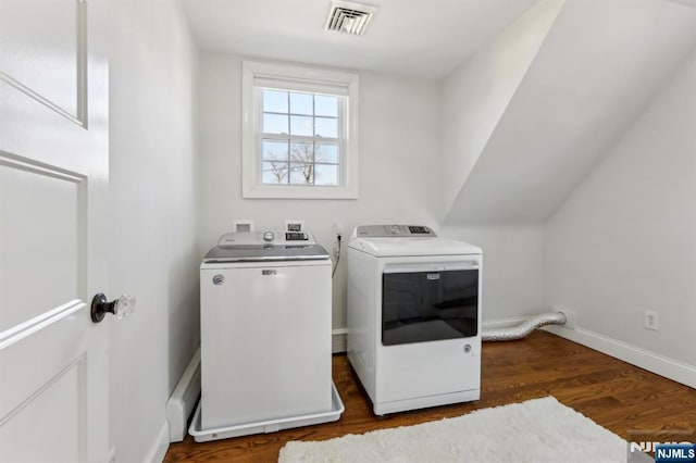 clothes washing area with visible vents, independent washer and dryer, laundry area, baseboards, and dark wood-style flooring