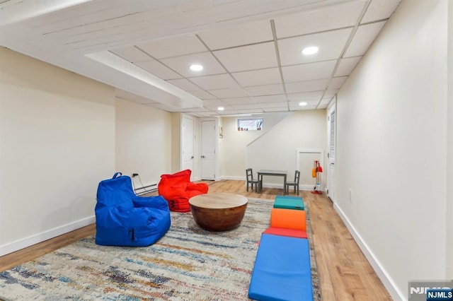 workout area with recessed lighting, a drop ceiling, baseboards, and wood finished floors