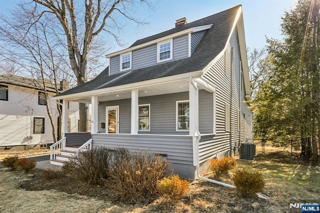 view of front of property with central air condition unit, covered porch, and a chimney