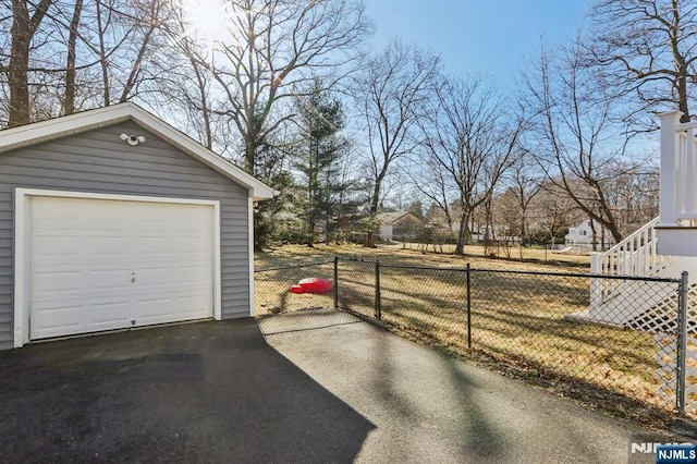 detached garage featuring fence and driveway