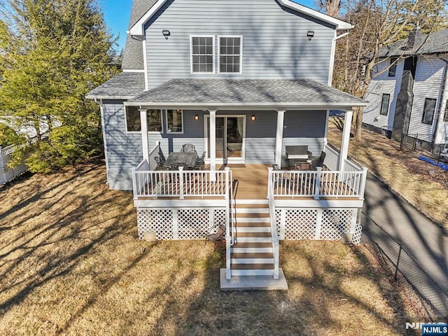 view of front of home with a front yard, roof with shingles, and fence