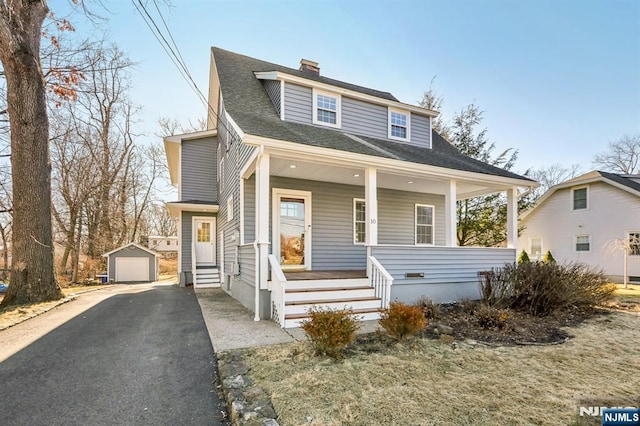 bungalow with a shingled roof, a detached garage, a porch, an outdoor structure, and driveway