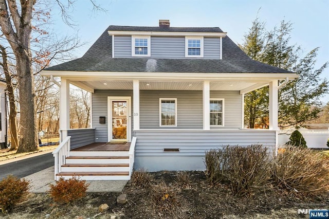 bungalow-style home with crawl space, covered porch, a chimney, and roof with shingles