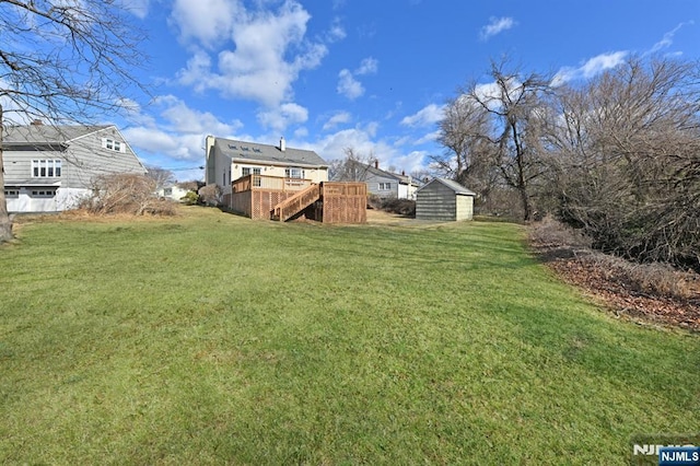 view of yard featuring stairway, a storage shed, an outdoor structure, and a deck