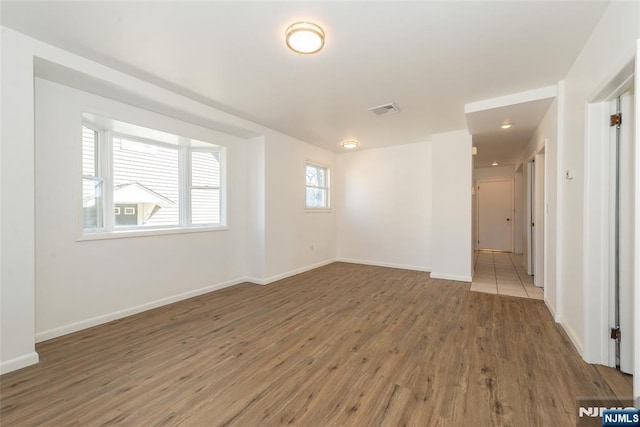 unfurnished room featuring visible vents, baseboards, and wood finished floors