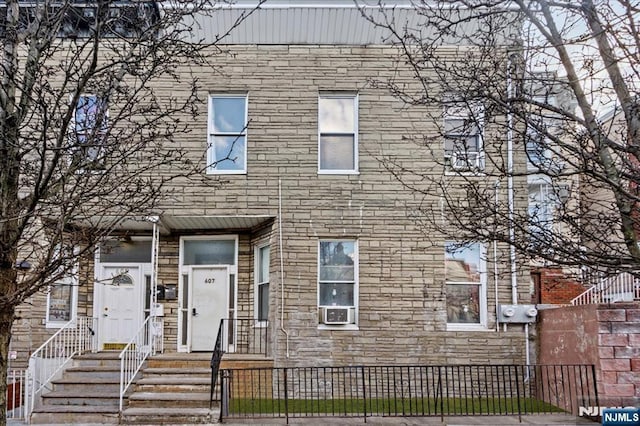 townhome / multi-family property with a fenced front yard and stone siding