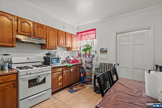 kitchen featuring white gas range, stainless steel microwave, crown molding, and under cabinet range hood