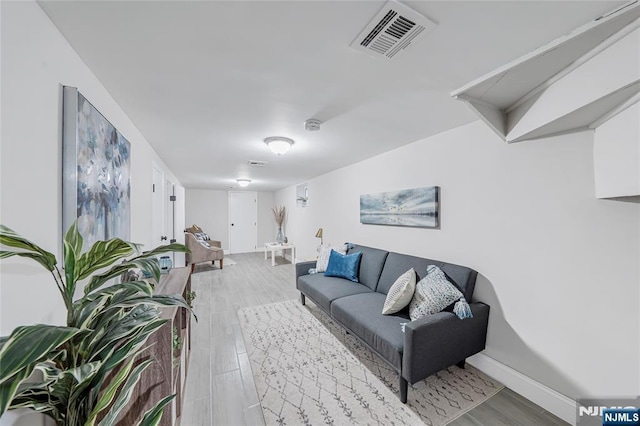 living area with visible vents, light wood-style flooring, and baseboards