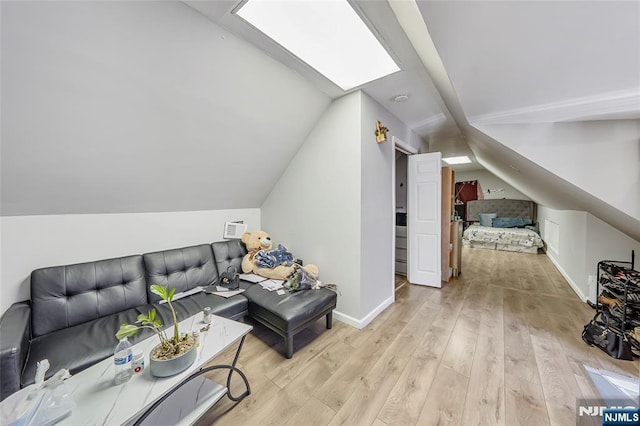 interior space featuring lofted ceiling with skylight, baseboards, and light wood-type flooring