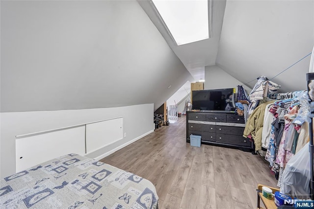 bedroom with lofted ceiling with skylight and light wood-type flooring