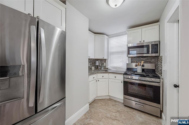 kitchen with tasteful backsplash, light stone counters, appliances with stainless steel finishes, white cabinetry, and a sink