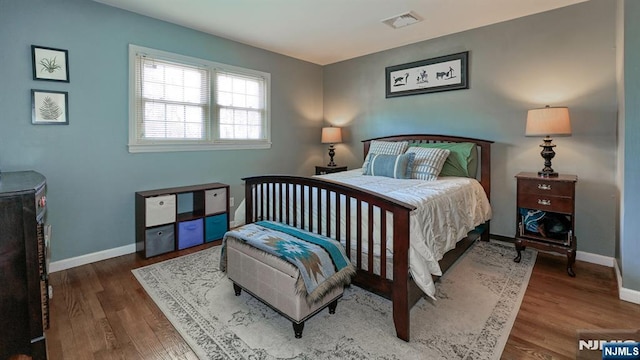 bedroom featuring wood finished floors, visible vents, and baseboards