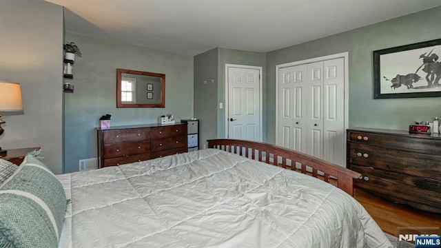 bedroom featuring wood finished floors, visible vents, and a closet