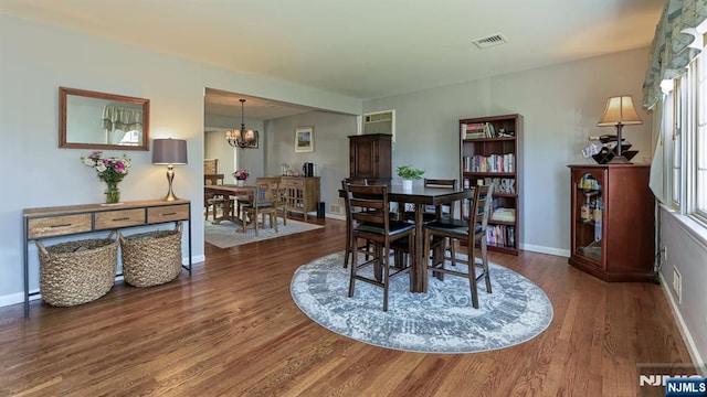 dining room featuring an inviting chandelier, wood finished floors, visible vents, and baseboards