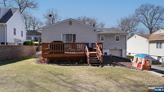 rear view of property with a wooden deck, a lawn, a garage, and fence