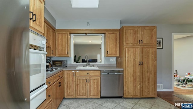 kitchen with a warming drawer, visible vents, a sink, stainless steel appliances, and light countertops