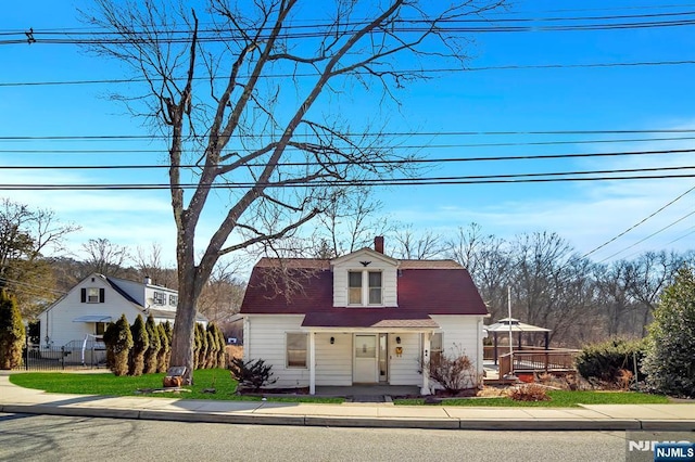 view of front of property with a fenced front yard, a gambrel roof, roof with shingles, and a chimney